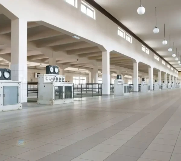 An industrial robot arm with a cleaning attachment extends over a large, smooth surface, possibly for automated cleaning in a factory or warehouse.